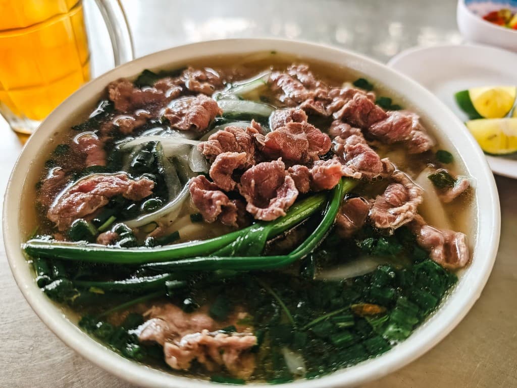 Bol de phở au bœuf, oignons nouveaux et bouillon.
